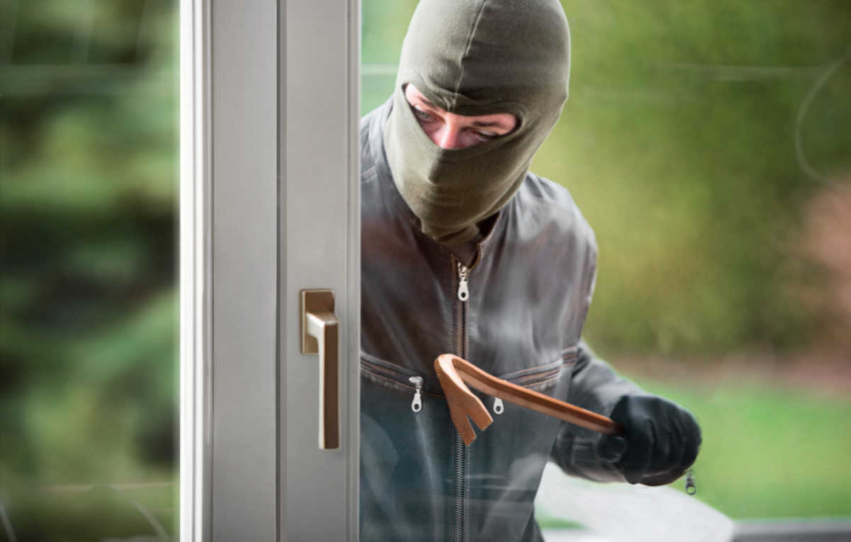A criminal with a crowbar outside the window